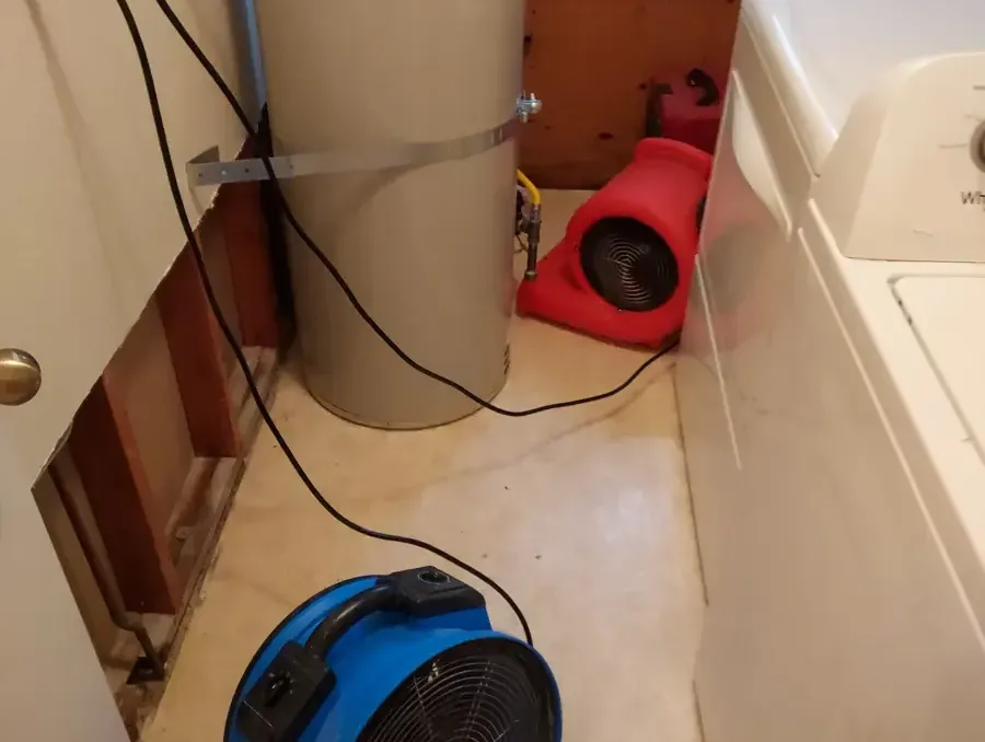 Air movers drying a laundry area with the wall opened behind the washer, an appliance leak drying