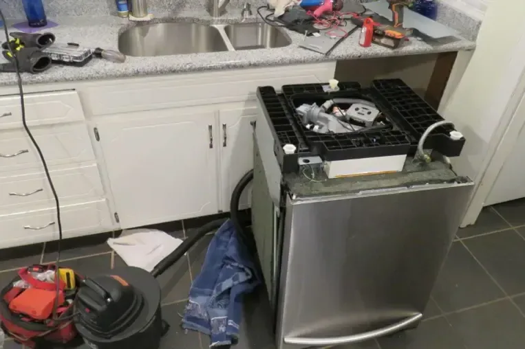 A dishwasher pulled forward beside extraction hoses and a wet vacuum